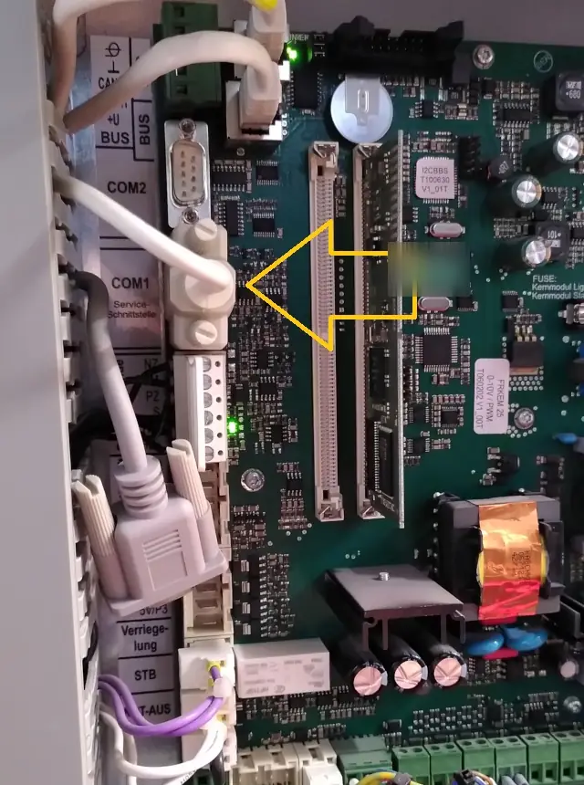 Close-up of the board: the COM2 and COM1 "Service-Schnittstelle" ports, with a serial cable plugged into COM1